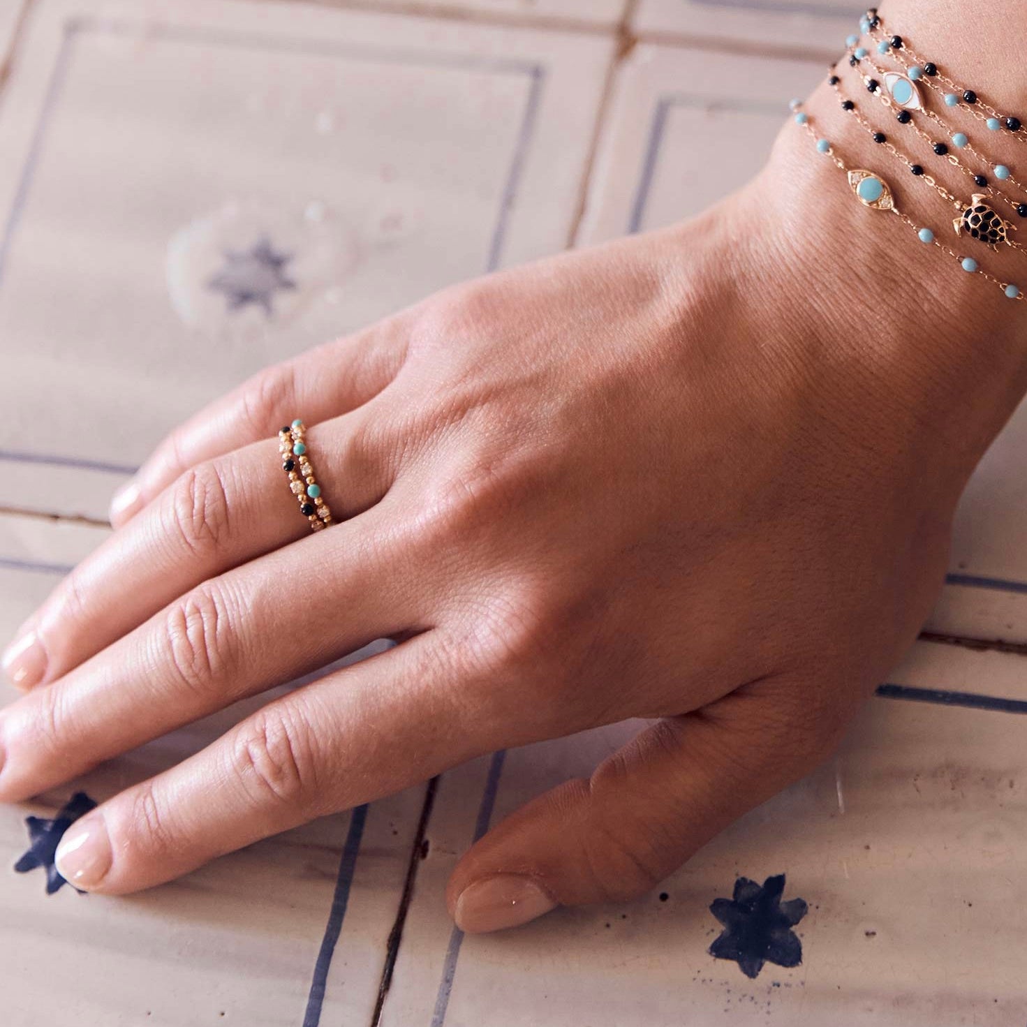 Photo de la main d’une femme portant deux bagues Gigi Clozeau de couleur turquoise et noire.