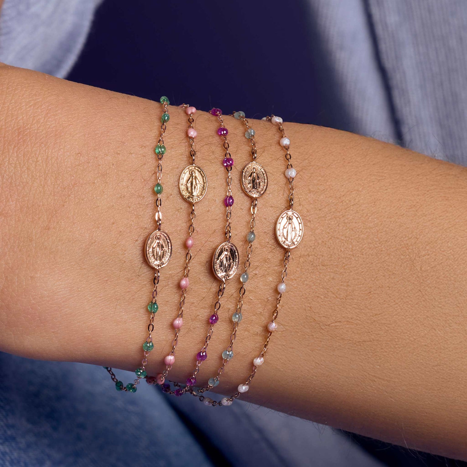"Photo du poignet d’une femme portant des bracelets 'Madone' Gigi Clozeau de différentes couleurs.