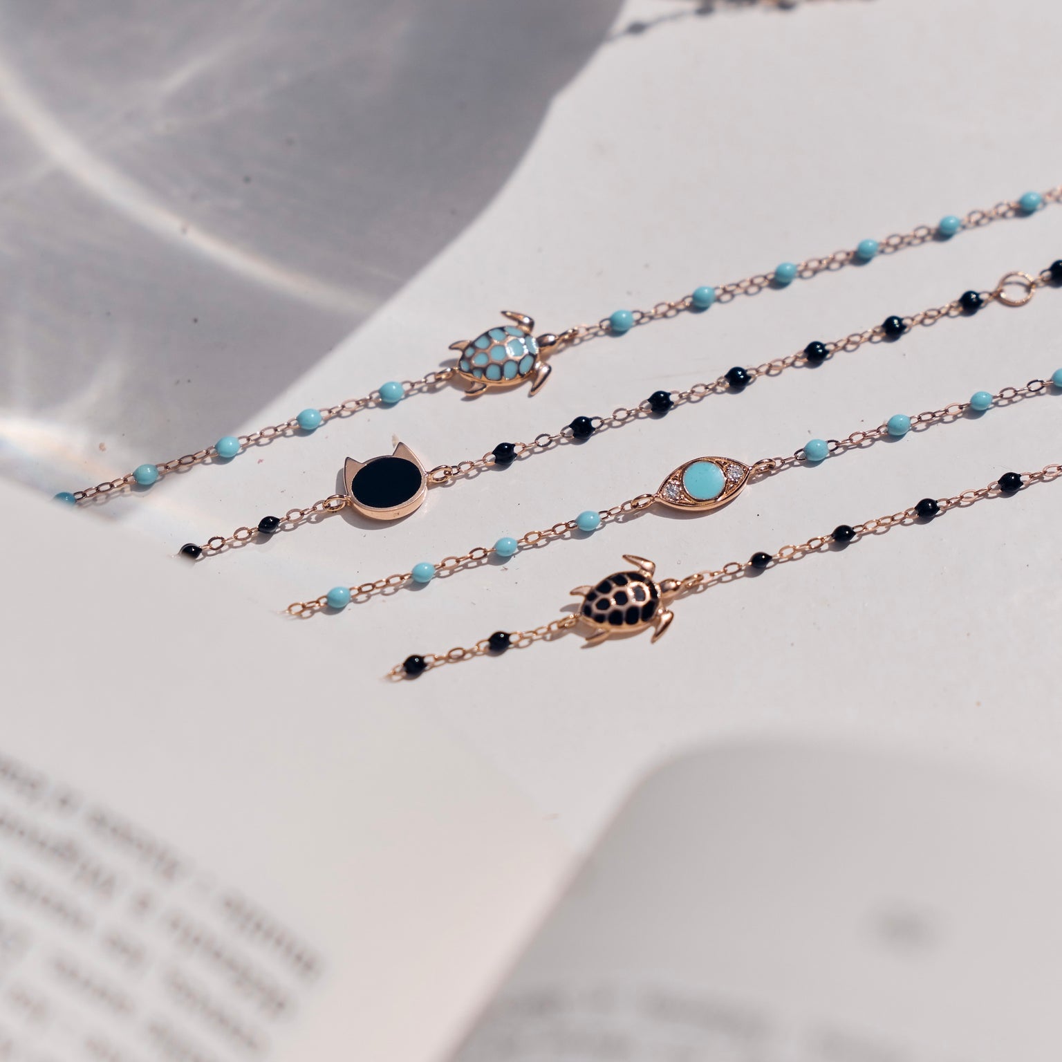 Photo de plusieurs bracelets Gigi Clozeau, aux couleurs noire et turquoise, disposés sur une table.