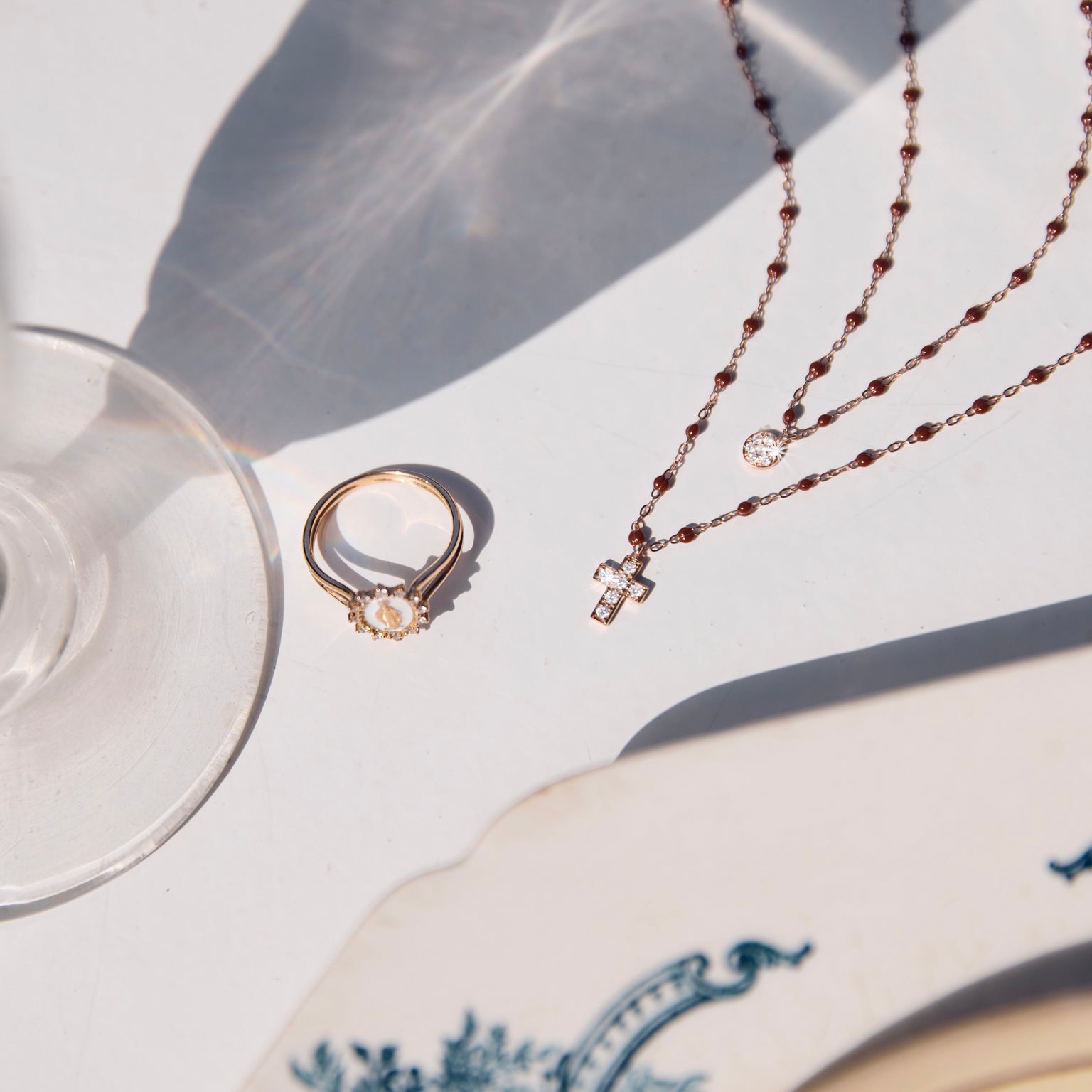 Photo d'une bague et de deux colliers Gigi Clozeau posés sur une table.