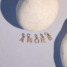 Photo de nature morte de plusieurs pendentifs Lucky Letters Gigi Clozeau posés, formant le mot « Amore ».